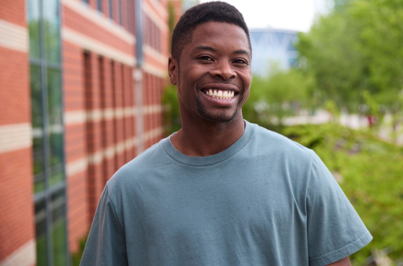 Man wearing a blue t-shirt smiling on SAIT campus