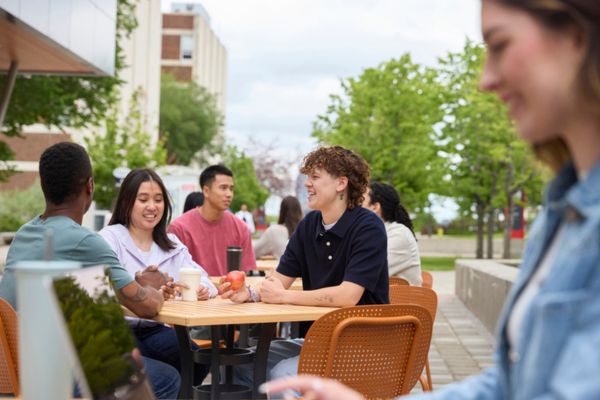 Students sitting at an outdoor table on SAIT campus smiling and eating